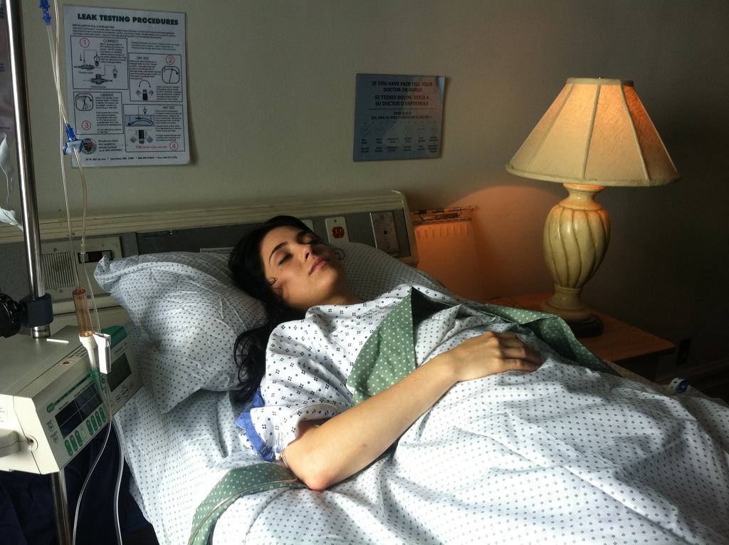 A woman is resting on a hospital bed