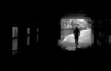 In a darkened tunnel, the silhouette of a human figure flees.