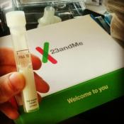A hand shows a sample collection tube from 23andMe kit.