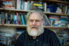 George Church is the central subject of the photo, with book shelves in the background.