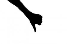 Silhouette of a hand gesturing with a "thumbs down," against a white background