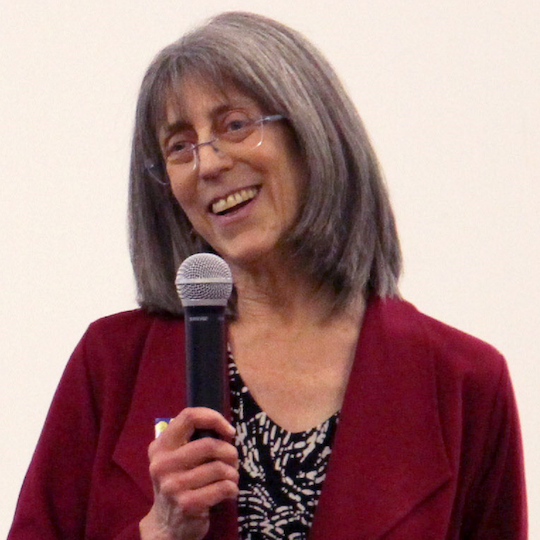 photo of Marcy Darnovsky holding a microphone