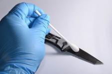 A gloved hand swabs a knife to collect DNA for evidence.