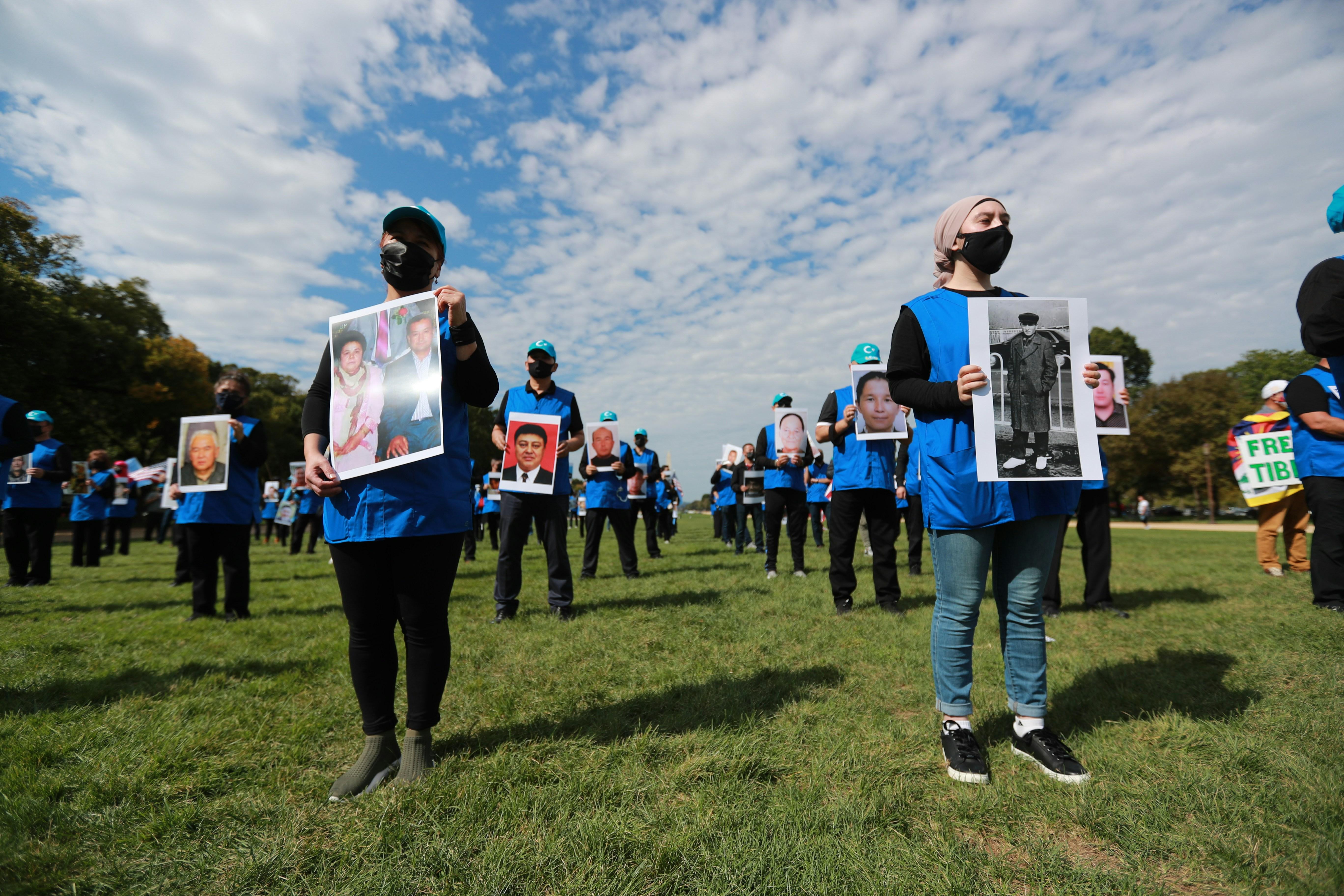 People standing on a field in blue clothing protesting the Uyghur genocide
