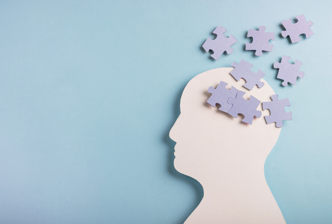 a cutout of a person's head with puzzle pieces on a blue background