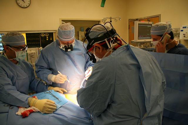 Four doctors surround a paitent undergoing surgery.