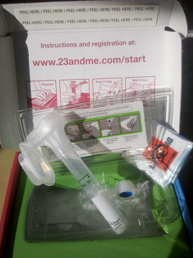 A 23andMe box is opened, revealing the spit kit equipment.