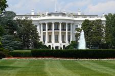 Frontal view of the White House is shown, with the lawn.