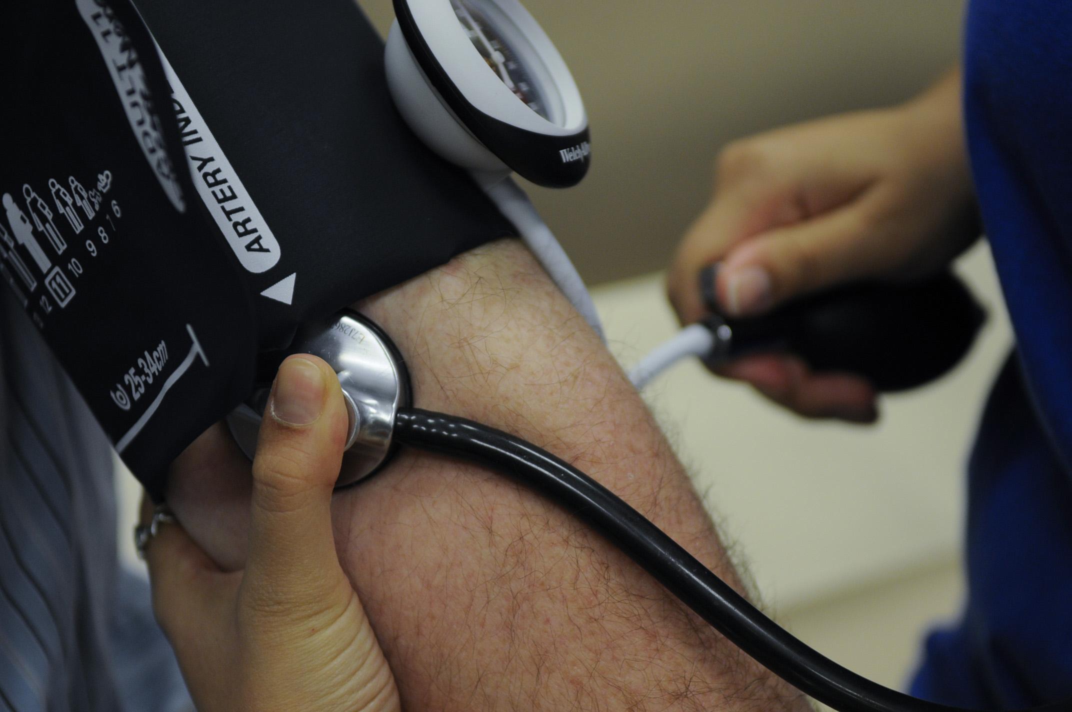 Blood pressure cuff around someone's arm and a stethoscope taking blood pressure 