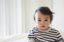 A young baby stares directly into the camera against a white background.