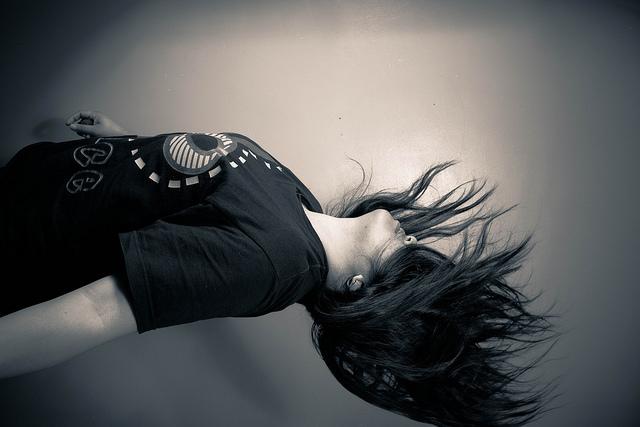 Gray scaled image, showing a woman who appears to be falling, with her hair covering her face and in motion.