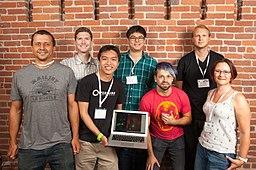 A group of Biohackers. In the middle, one of the members holds an Apple laptop. Josiah Zayner  stands beside the laptop