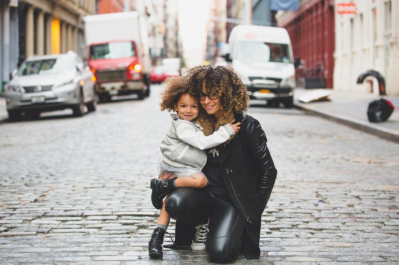 Mother and child holding each other and posing in the street. 