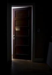 A crack of light pours into a barely opened door.